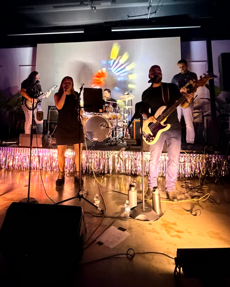 The Pollies playing live on stage under coloured stage lights