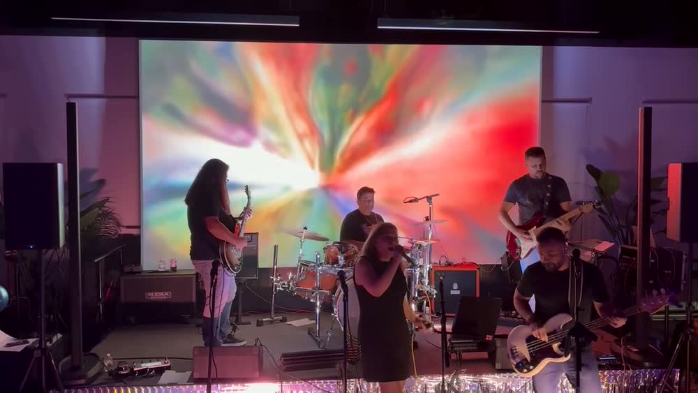The full band playing together on a lit stage
